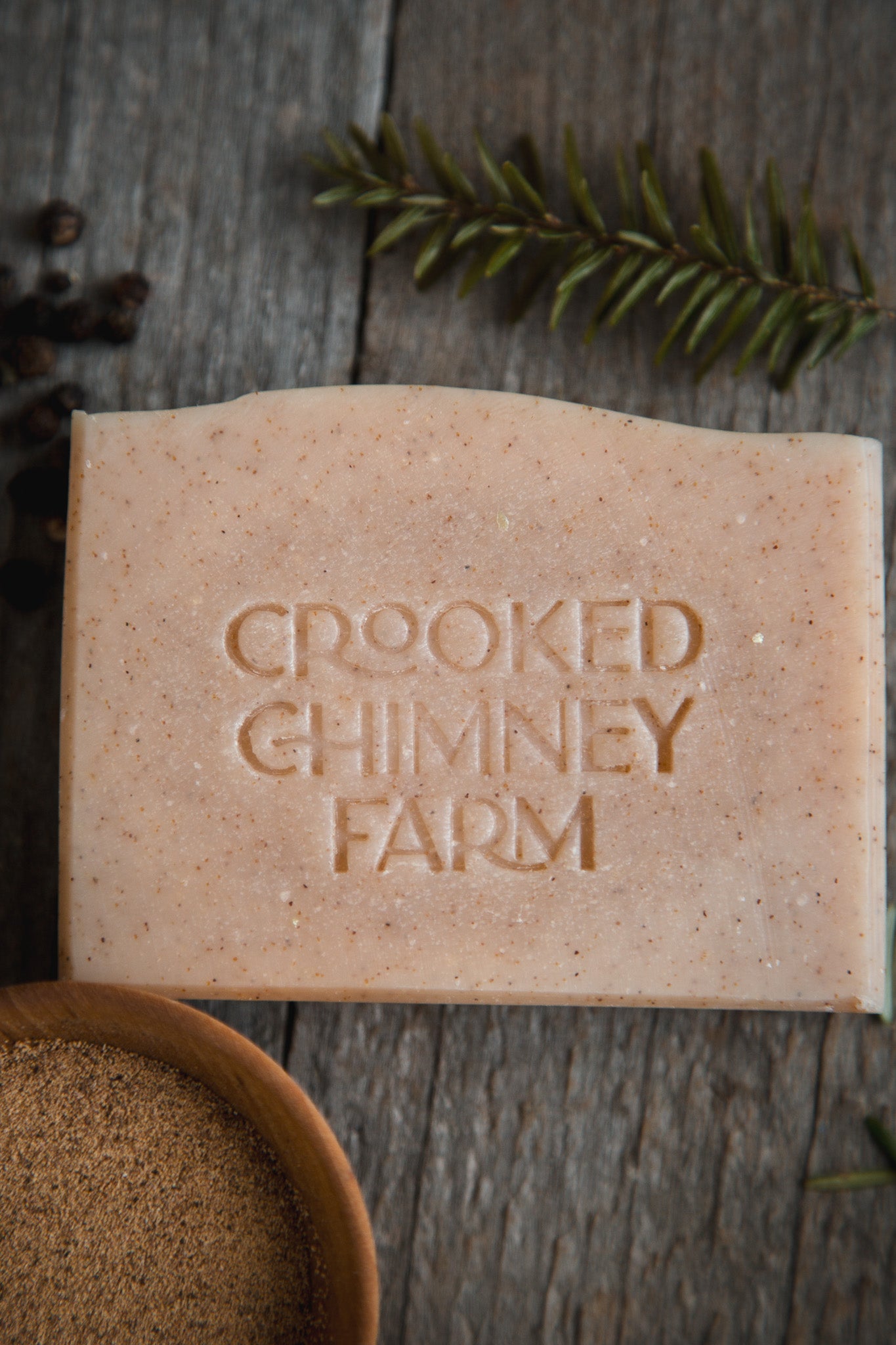 a bar of north woods soap on wood background with walnut shell, pepper corns and evergreen sprig