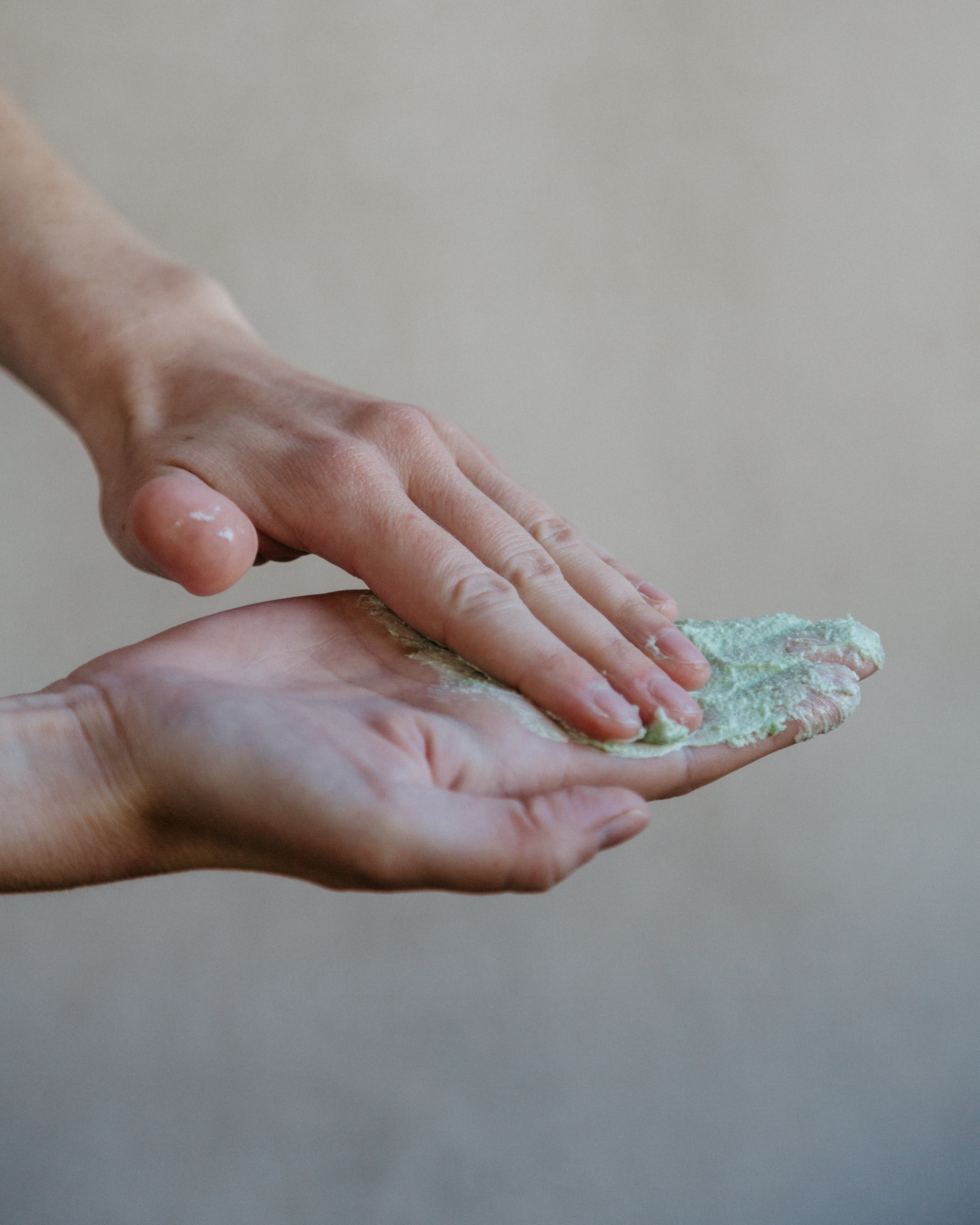 Two hands spreading tobacco and bay leaf sugar whipped soap. 