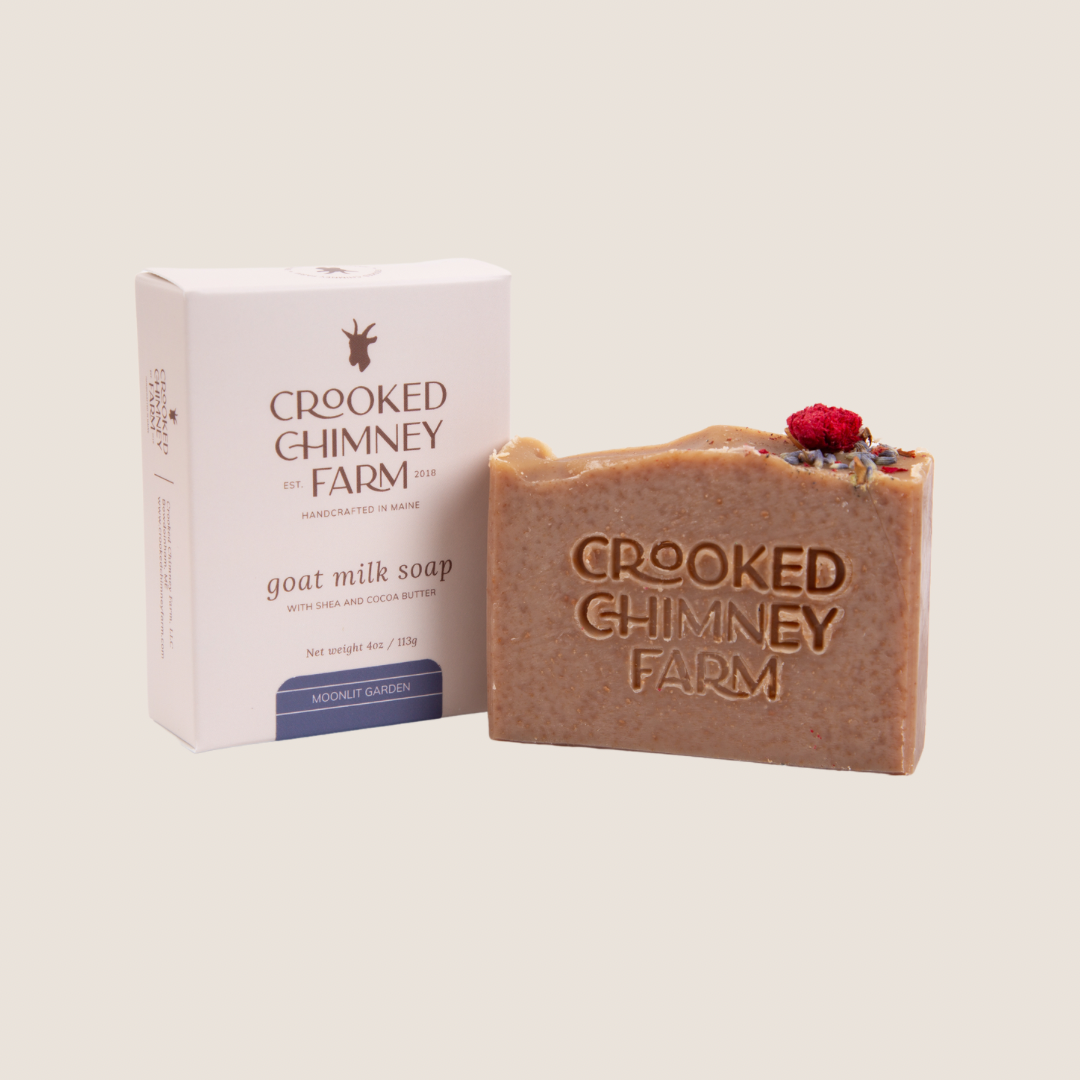 A bar of crooked chimney farm Moonlit Garden goat milk soap set next to soap box