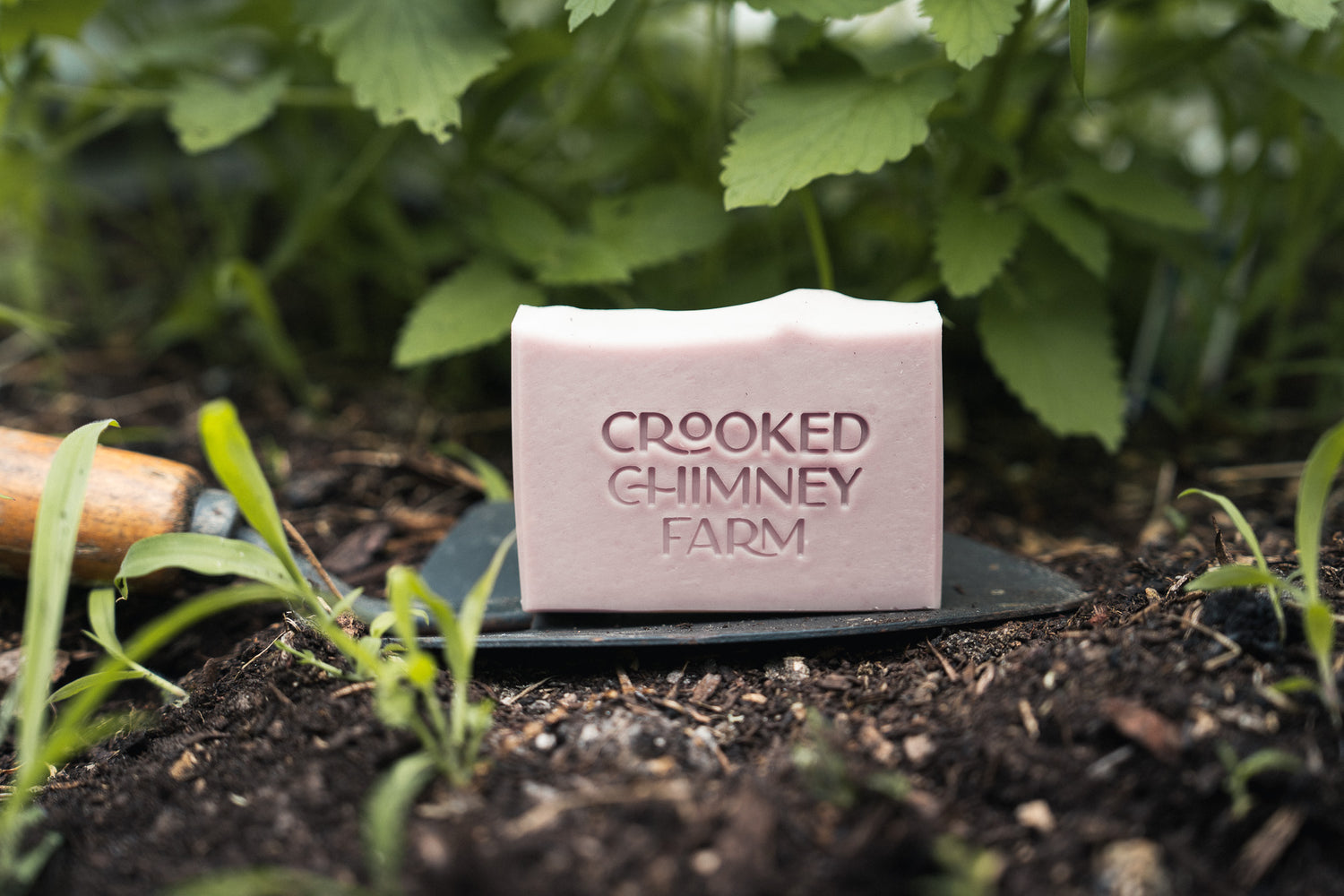 a bar of crooked chimney farm Garden soap on a trowel in a garden
