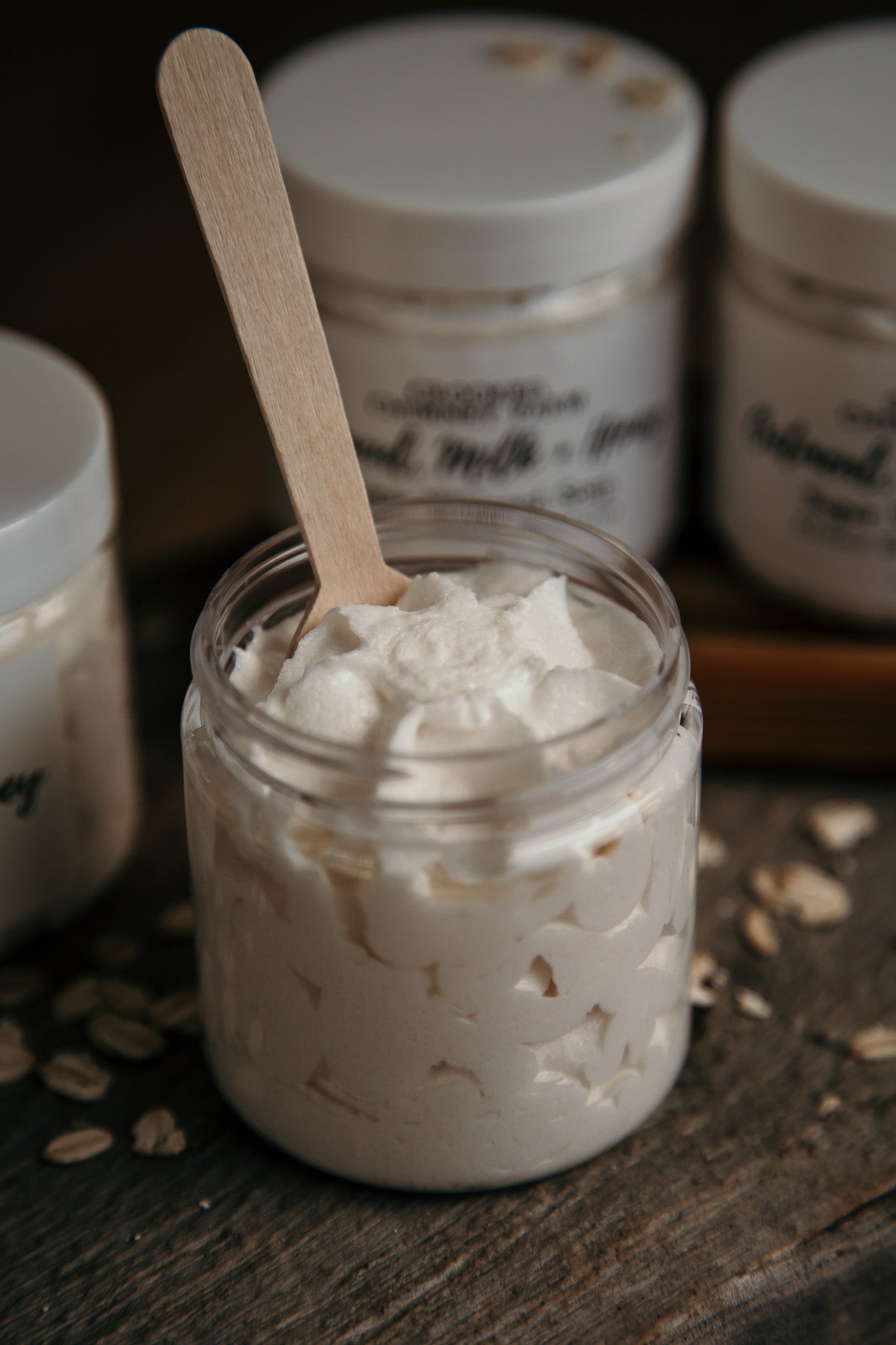 oatmeal milk and honey sugar whipped soap, open jar with wood spoon in it. 