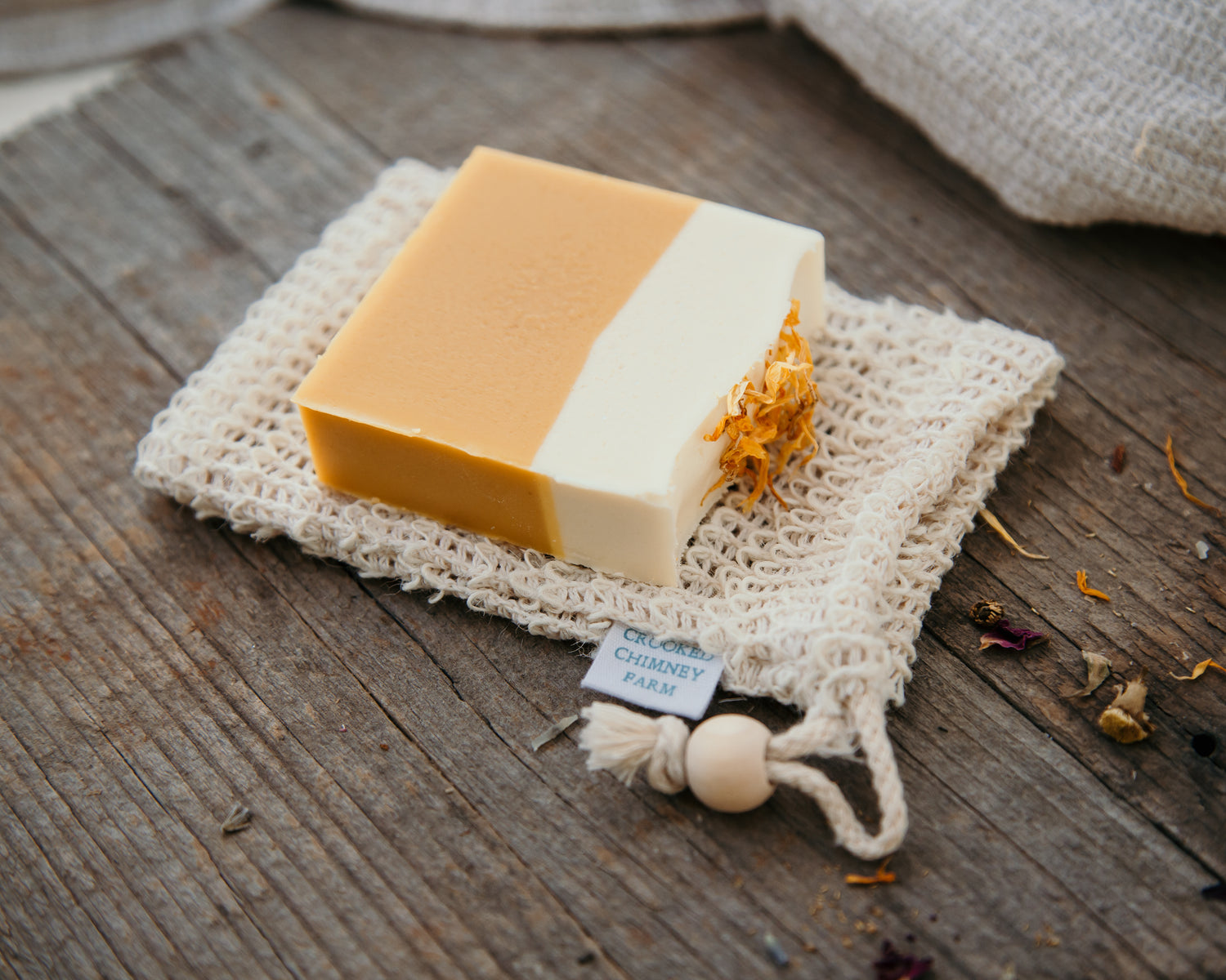 soap saver pouch underneath a bar of yellow and white soap. 