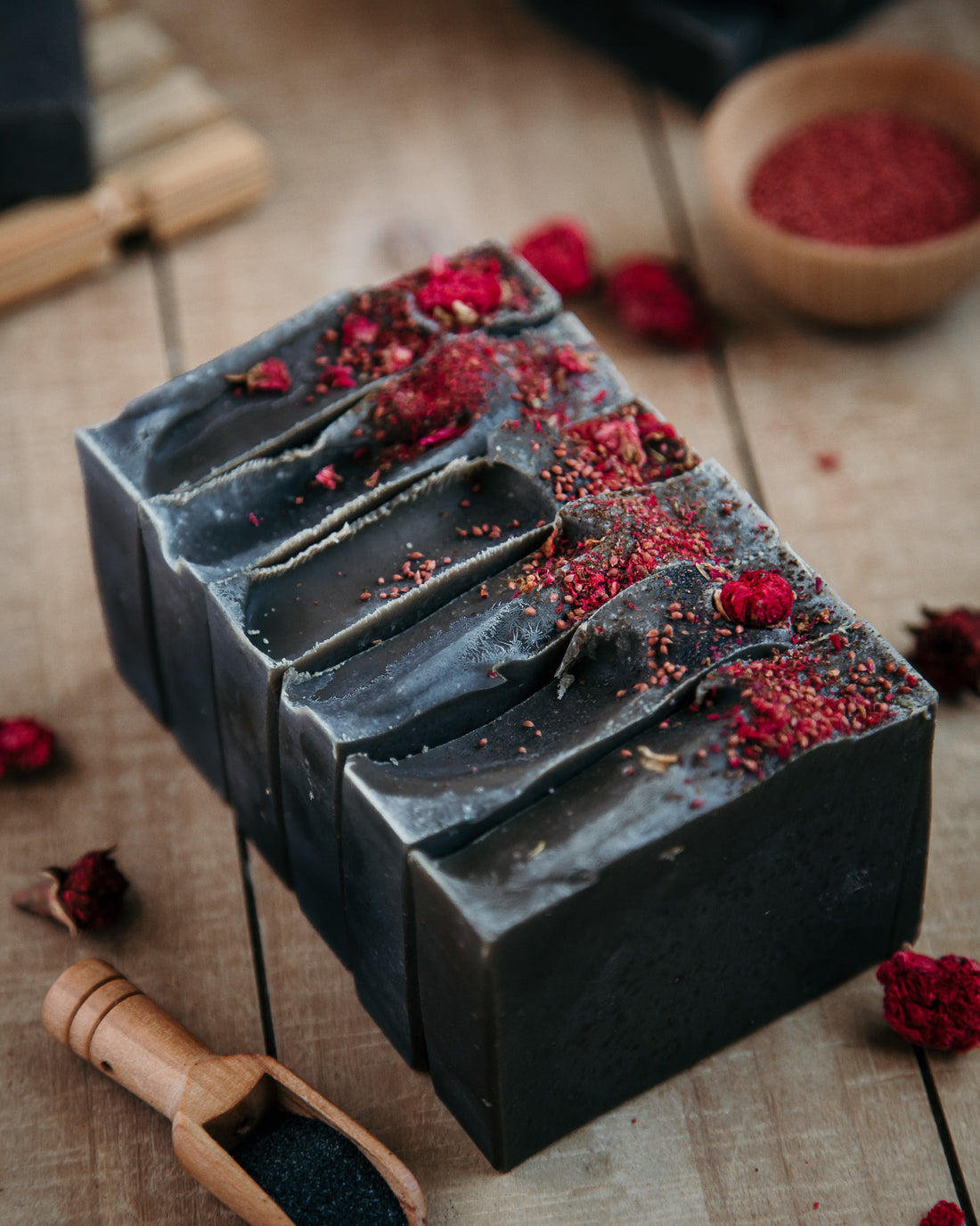 a loaf of bad blood soap sup into bars. Bowls and scoops of ingredients in the background. 